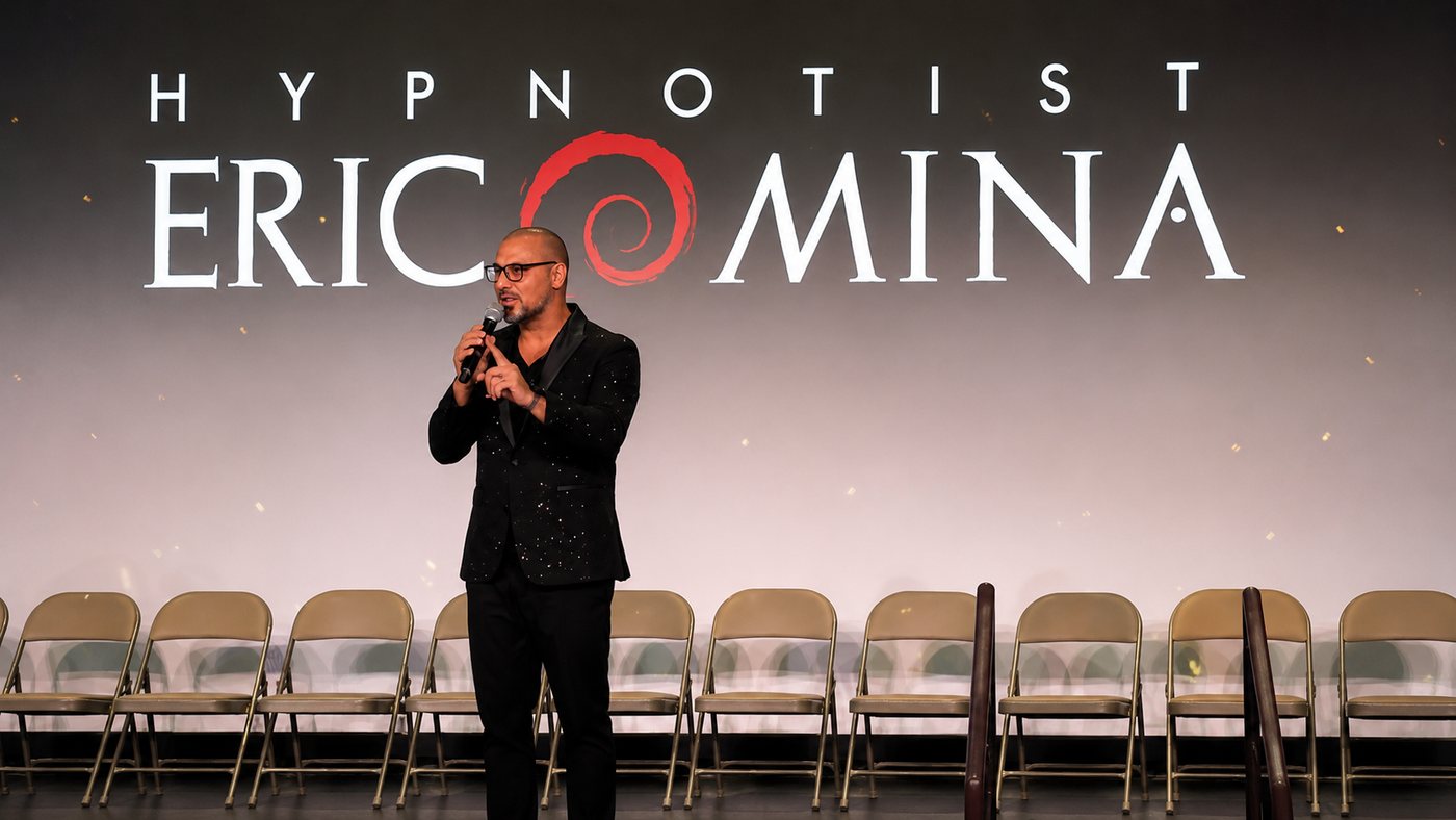 Eric Mina on stage in front of his name on the big screen